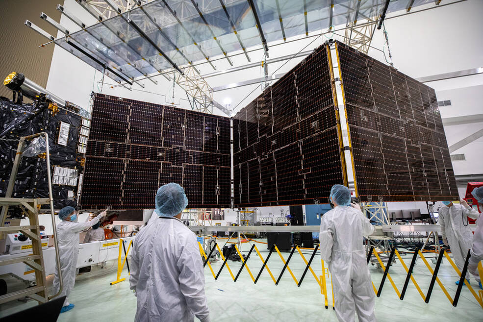 Technicians working beside one of the Psyche spacecraft's large solar arrays during launch preparations in Florida.