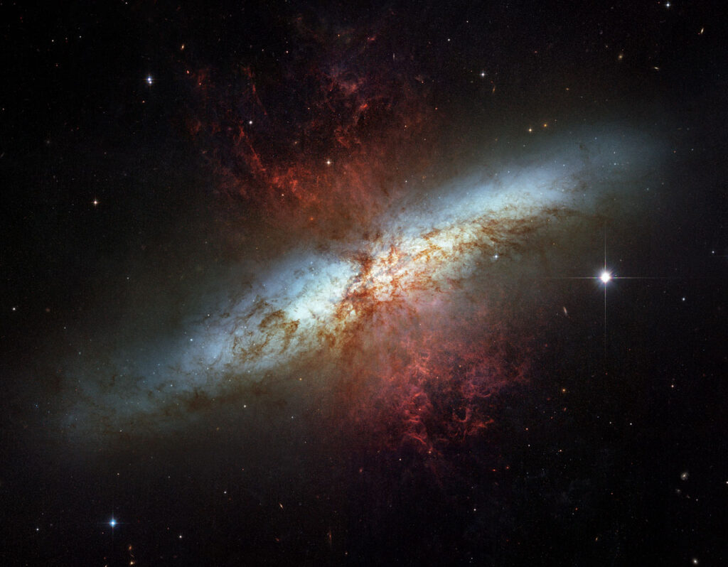 Hubble image of the Cigar Galaxy M82 with red plumes of hydrogen streaming from its core