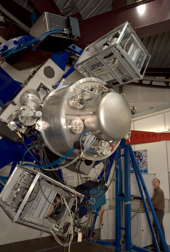 The X-shooter spectrograph, a boxy instrument with a central cryostat, mounted on a test rig in a laboratory
